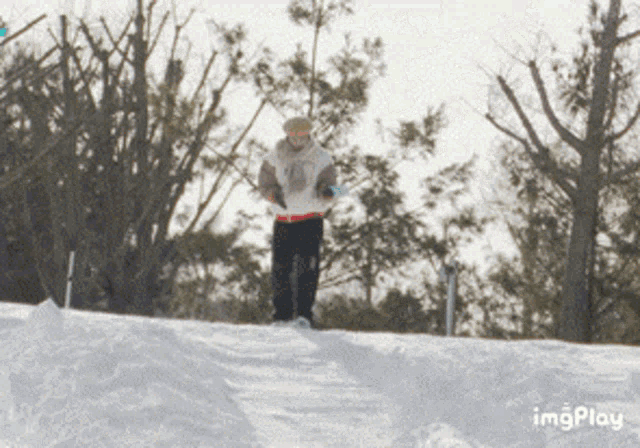 a person is skiing down a snow covered slope with trees in the background and the word imgplay below them