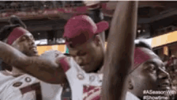 a group of basketball players are standing next to each other in a stadium and shaking hands .