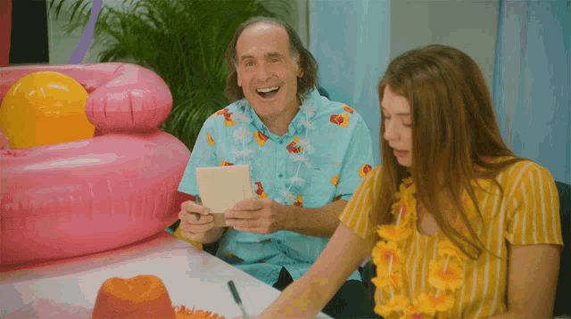 a man in a hawaiian shirt is holding a piece of paper