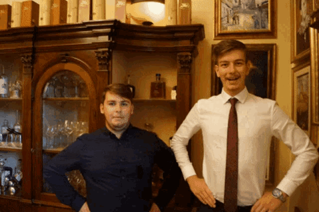 two men are standing next to each other in front of a cabinet