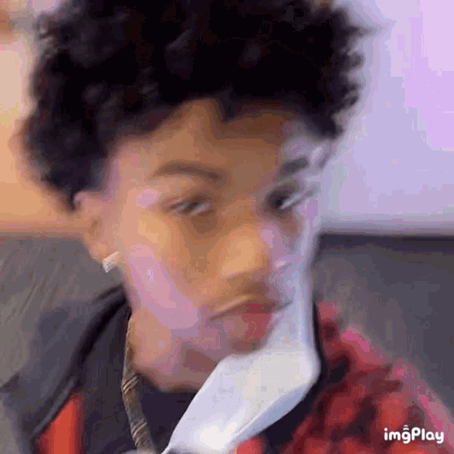 a young man with curly hair is wearing a mask on his face .
