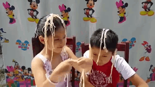 a boy and a girl are playing with noodles and the girl is wearing a shirt that says brooklyn