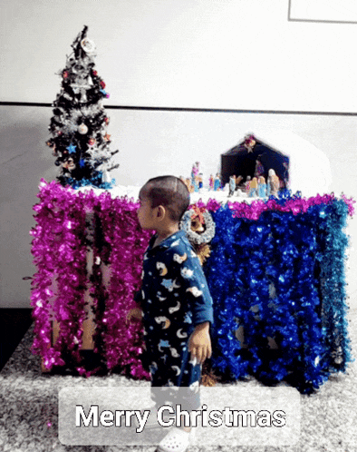 a little boy standing in front of a christmas scene with the words merry christmas written on the bottom