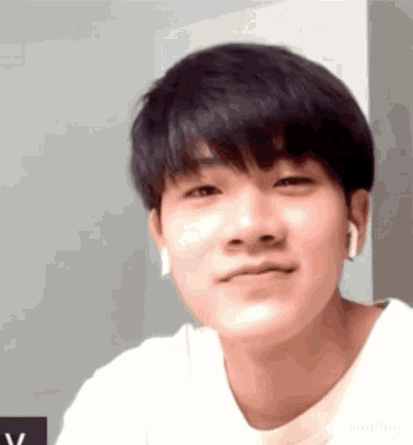 a young man wearing a white shirt and headphones is smiling .