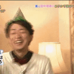 a man wearing a party hat is smiling in a room with chinese writing on the wall