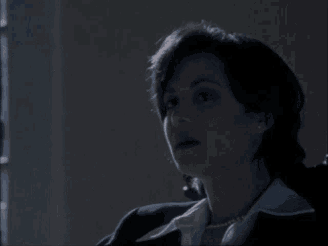 a woman is sitting in a dark room and looking at the camera