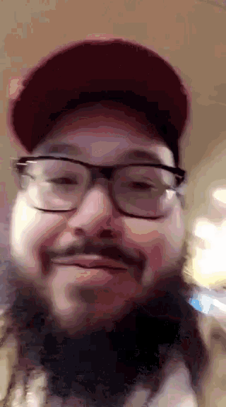 a man with a beard and glasses is wearing a red hat