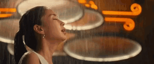 a woman is singing in the rain in front of a sign that says ' j ' on it .