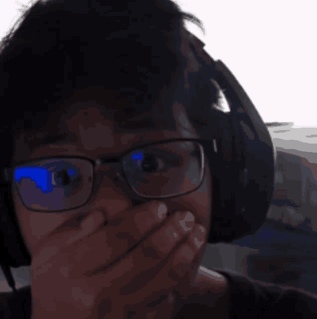 a man wearing glasses and headphones covering his mouth