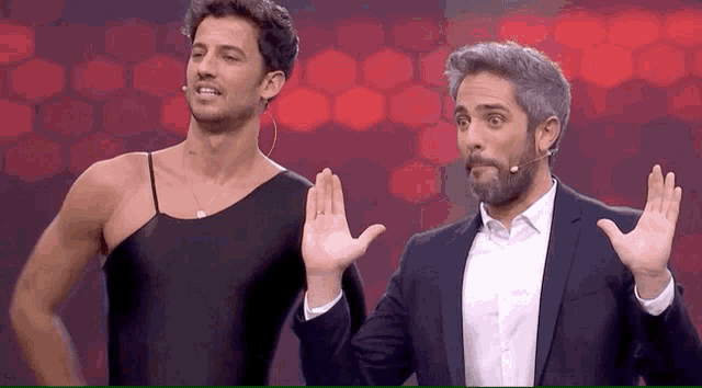 two men are standing next to each other on a stage and one of them is wearing a black leotard .