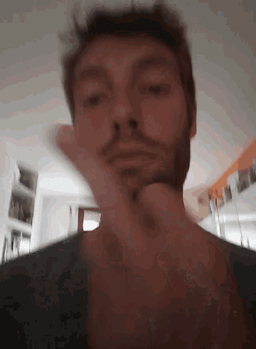 a man with a beard is making a funny face with his hand