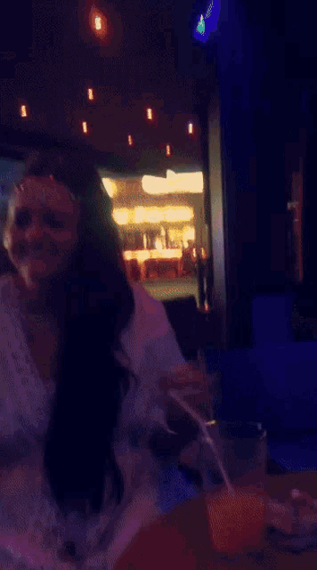 a woman sits at a table with a drink and a cigarette
