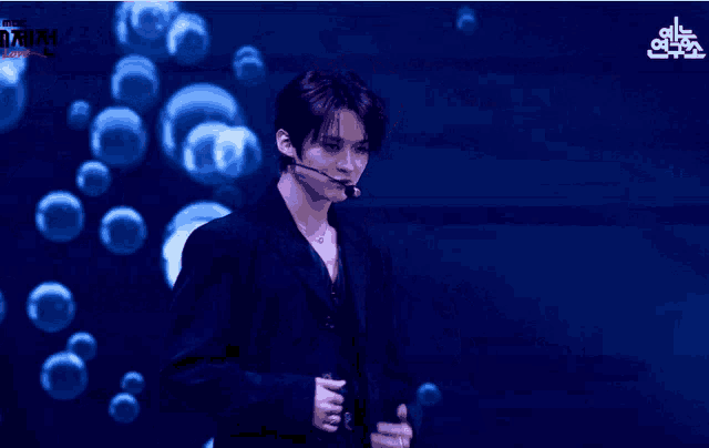 a man wearing a microphone stands in front of bubbles and a sign that says mbc on it