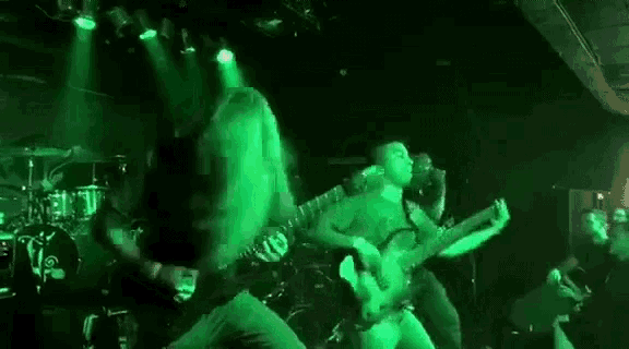 a man with a beard is playing a guitar on a stage in a dark room .