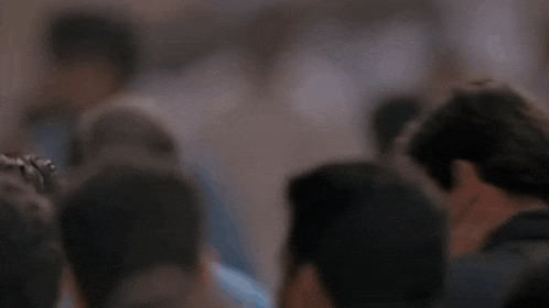 a man stands in a crowd of people and looks at the camera