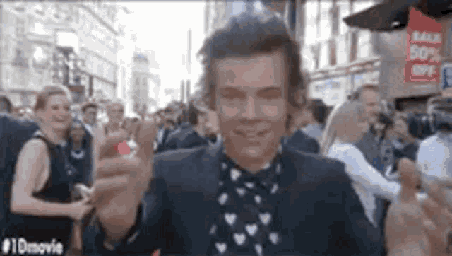 a man in a suit and polka dot shirt is standing in front of a crowd of people .