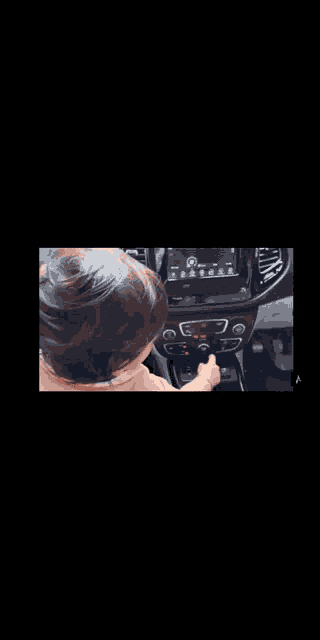 a little girl is sitting in a car and looking at the dashboard .