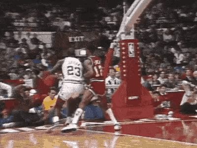a basketball player in a white jersey with the number 23 on it is jumping over another player .