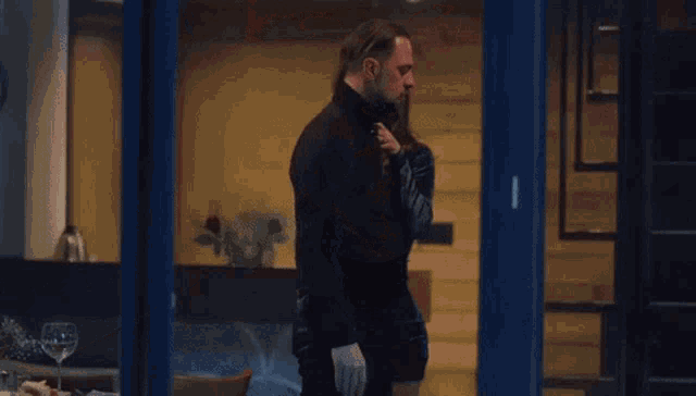 a man with a beard and a black turtleneck is being held by a woman .