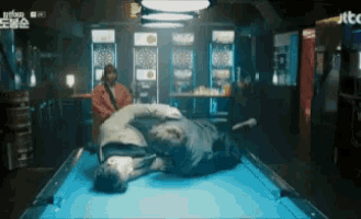 a man is laying on top of a pool table in a bar