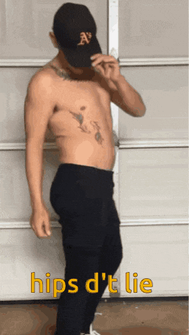 a shirtless man is standing in front of a garage door wearing a hat with the letter a on it .