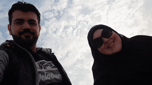 a man and a woman are posing for a picture and the man is wearing a veloban shirt
