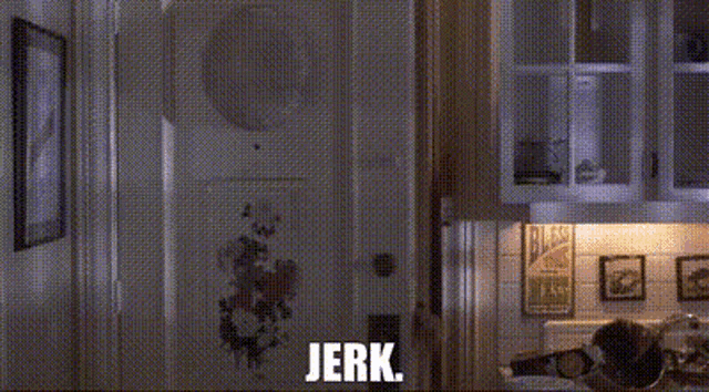a woman is standing in a kitchen with the words `` jerk '' written above her .