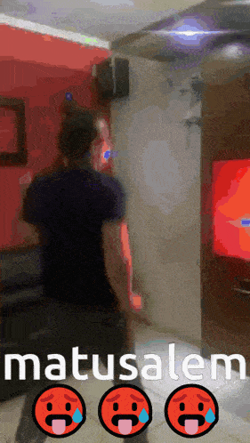 a man in a black shirt is standing in a living room with the words matusalem on the bottom right