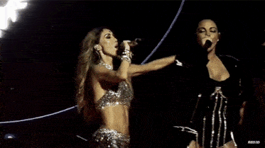 a woman singing into a microphone next to a man with the word riojd written on the bottom