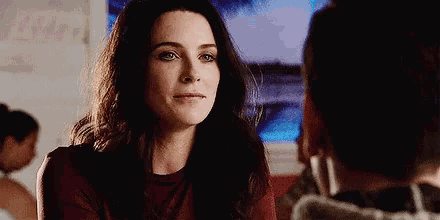 a woman in a red shirt is looking at a man in a restaurant .