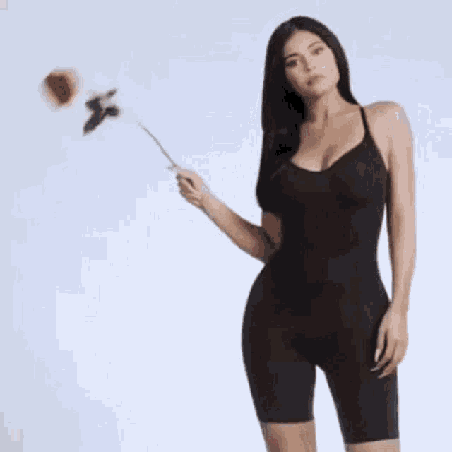 kylie jenner is wearing a black dress and holding a red rose .