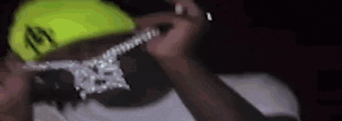 a close up of a man wearing a neon yellow hat and a necklace .