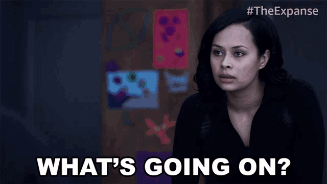 a woman says what 's going on in front of a wall of paintings