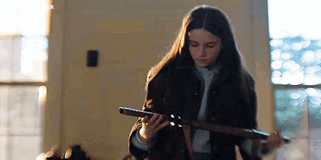 a young woman is holding a gun in her hand in a living room .