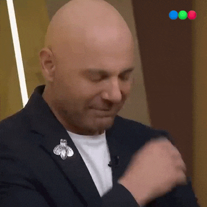 a bald man wearing a suit and a brooch with a bee on it is smiling .