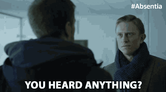 a man in a suit and scarf is talking to another man and says you heard anything