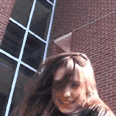a woman is standing in front of a brick building and smiling .
