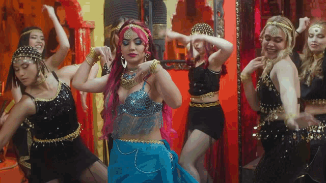 a woman with pink hair is dancing with a group of women