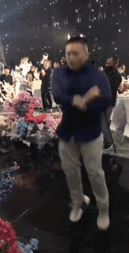 a man in a blue shirt is dancing in a crowd of people