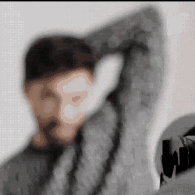 a blurry picture of a man in a sweater with his arm outstretched .