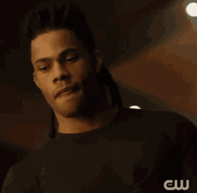 a man with dreadlocks is standing in a dark room .