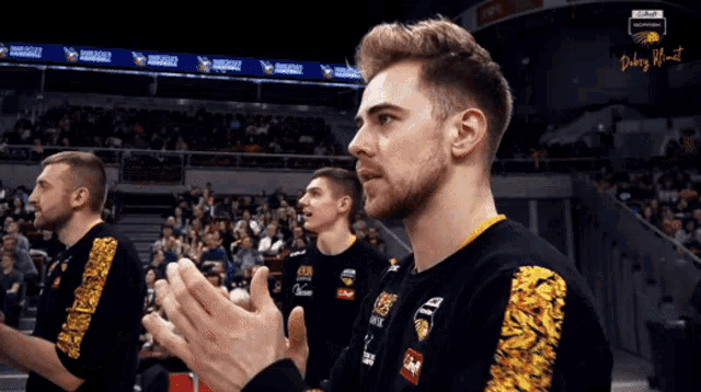 a group of men are clapping their hands in a stadium with a banner that says renault on it