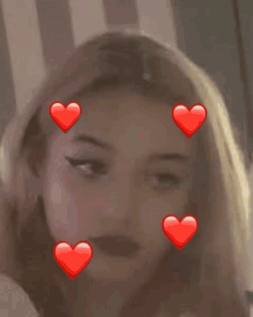 a close up of a woman 's face with red hearts on it .