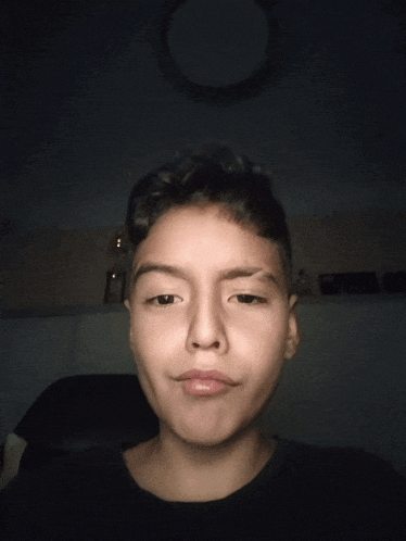 a young boy is making a funny face in a dark room