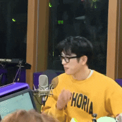 a man wearing glasses and a yellow sweater with the word horia on it