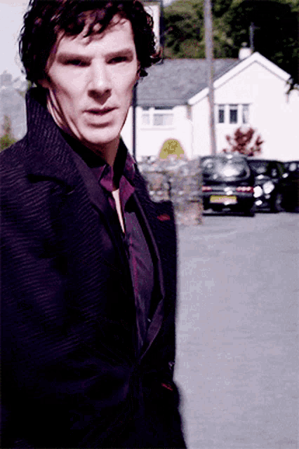 a man in a purple jacket stands in front of a car that has a license plate that says ' yfk '