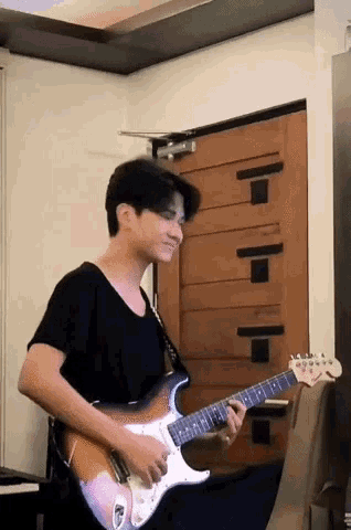a young man is playing an electric guitar in front of a door