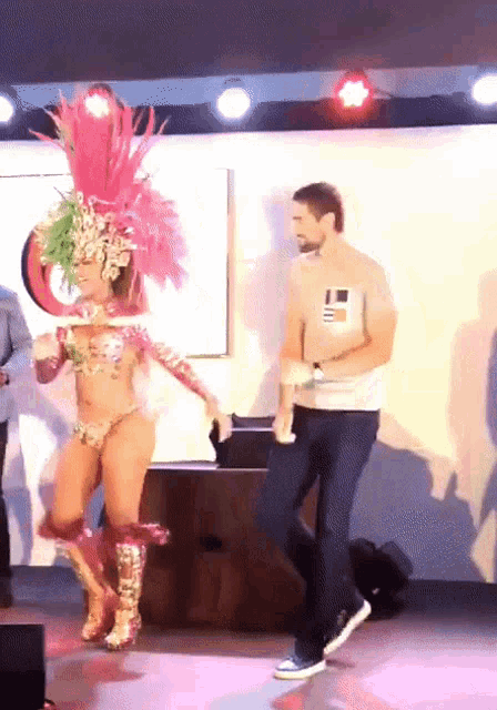 a man stands next to a woman in a costume with feathers