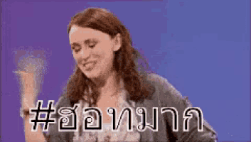 a woman is smiling and dancing in front of a purple background with a hashtag in a foreign language .