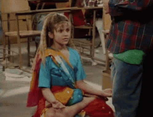 a young girl in a colorful dress is sitting on the floor .